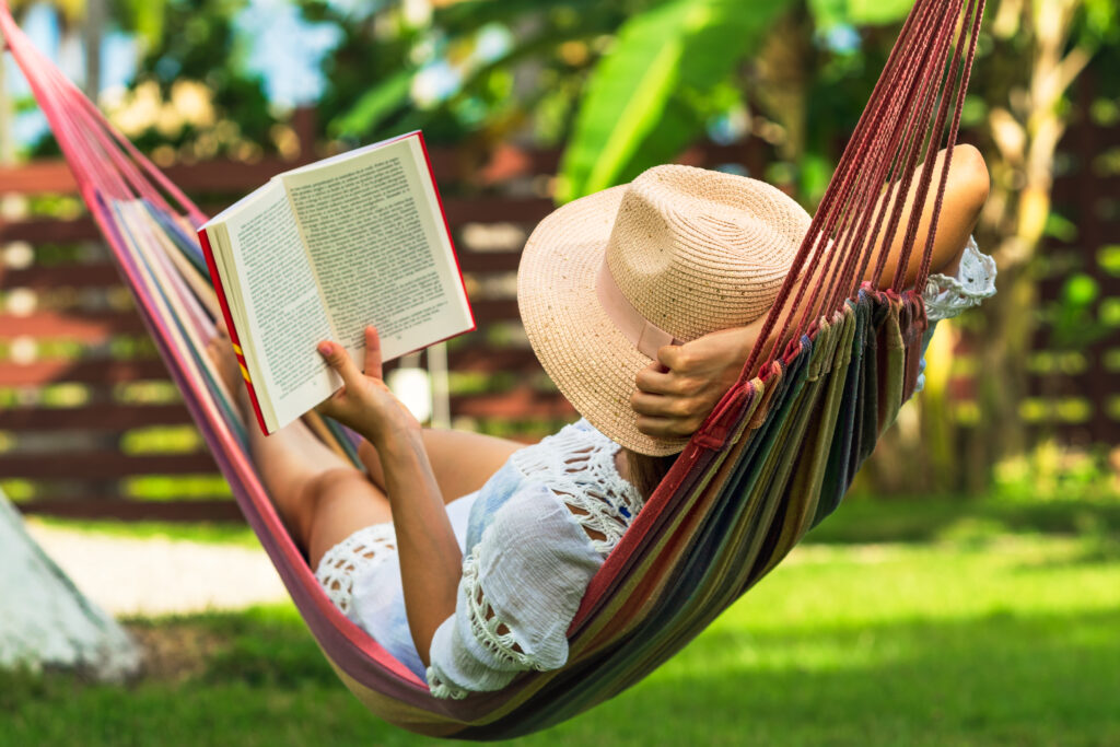 Mental Wellness Woman reading book in hammock in tropical garden